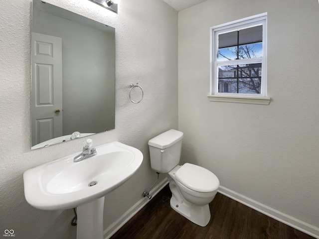 half bathroom featuring baseboards, toilet, and wood finished floors