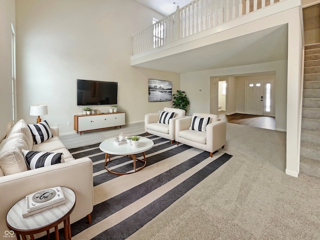 living area featuring baseboards, carpet floors, and a towering ceiling