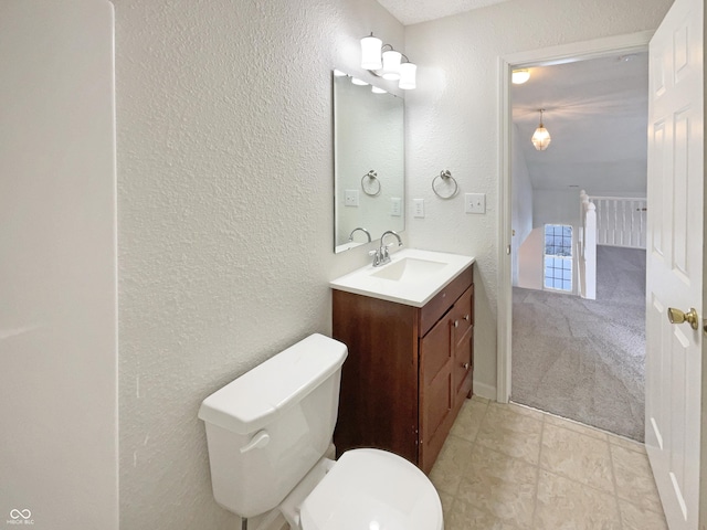 bathroom with vanity, toilet, and a textured wall