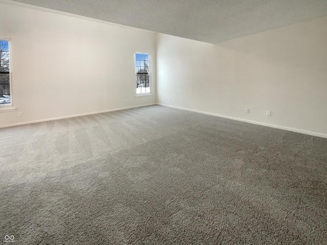 carpeted empty room with baseboards and a textured ceiling