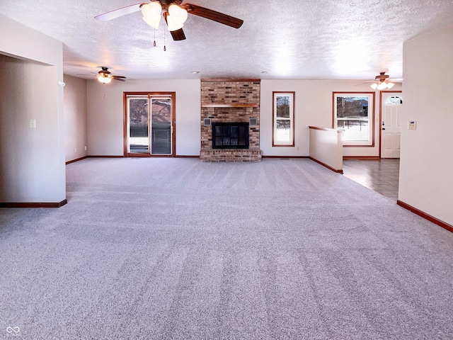 unfurnished living room with a brick fireplace, a textured ceiling, baseboards, and carpet floors