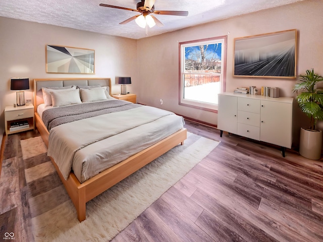 bedroom with ceiling fan, a textured ceiling, and wood finished floors