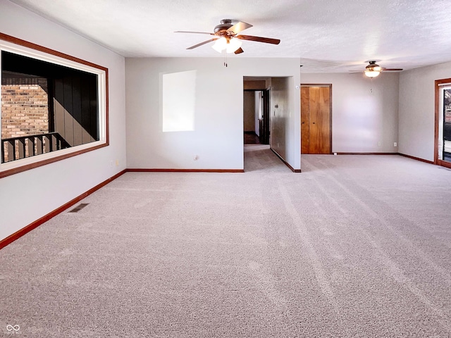 carpeted empty room featuring ceiling fan, baseboards, visible vents, and a textured ceiling