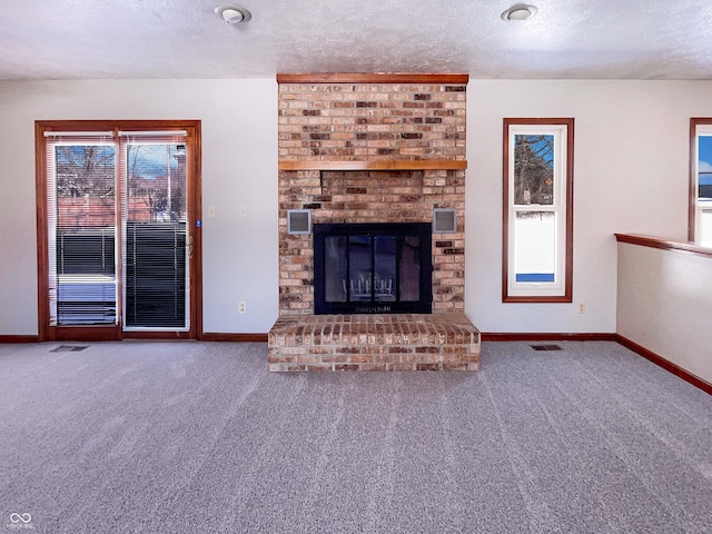 unfurnished living room featuring visible vents, a brick fireplace, a textured ceiling, and carpet floors