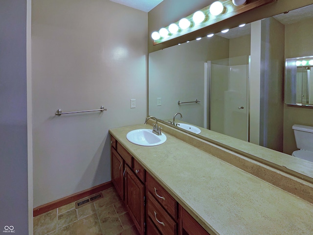 bathroom featuring visible vents, toilet, a shower stall, baseboards, and vanity