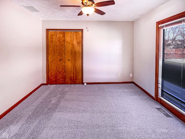 carpeted spare room featuring baseboards, visible vents, and a textured ceiling