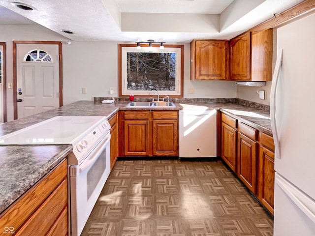 kitchen featuring white appliances, brown cabinetry, and a sink