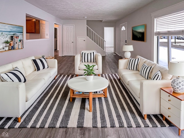 living room with a textured ceiling, stairs, and wood finished floors