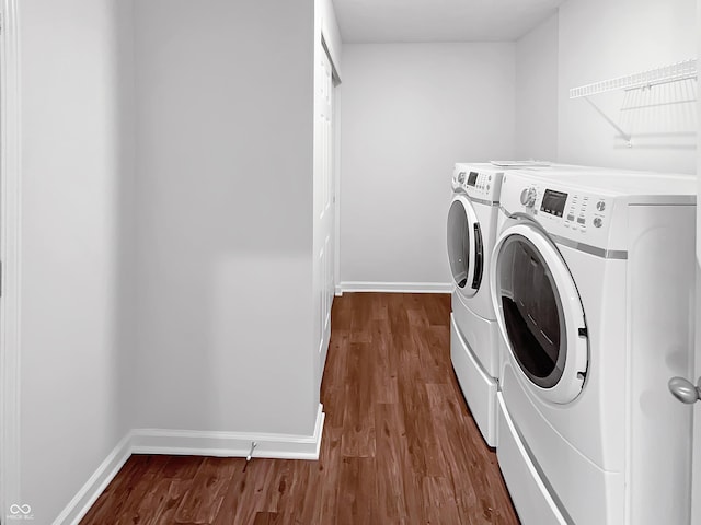 laundry area featuring laundry area, dark wood-style floors, baseboards, and washing machine and clothes dryer