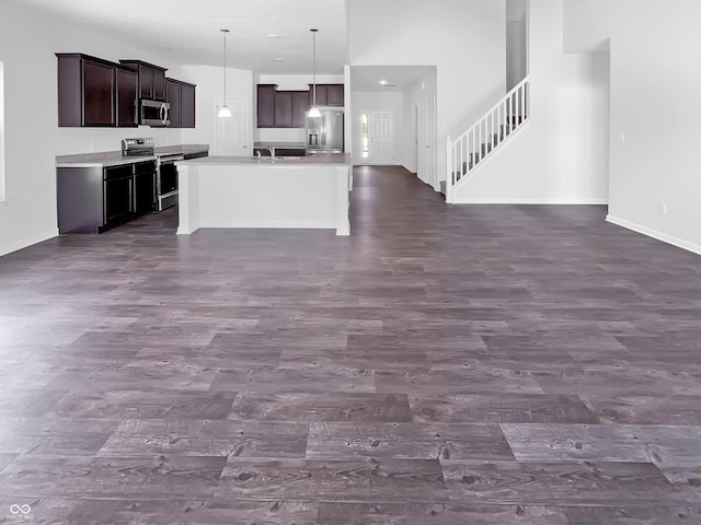 kitchen with dark wood-type flooring, baseboards, open floor plan, and stainless steel appliances