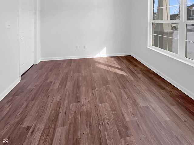 unfurnished room with baseboards, a healthy amount of sunlight, and dark wood-style flooring