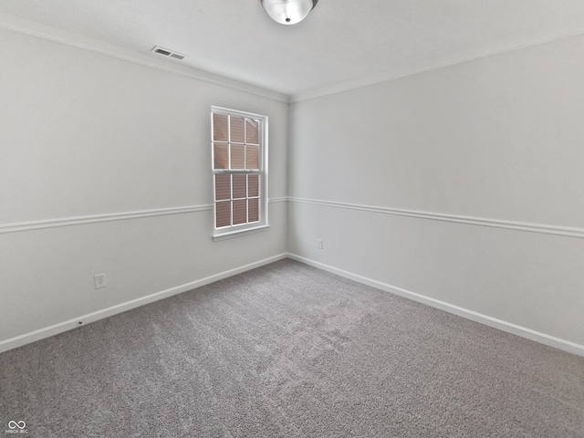 spare room featuring crown molding, carpet flooring, baseboards, and visible vents