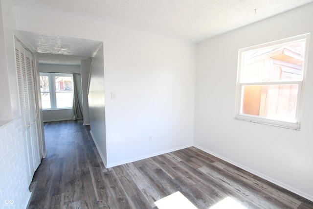 empty room with baseboards, a textured ceiling, and wood finished floors