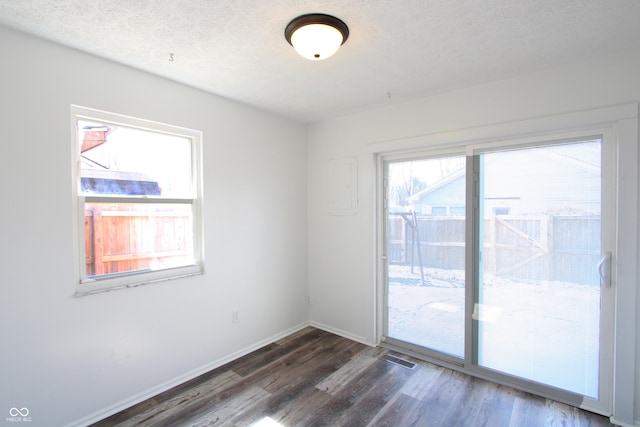 spare room with visible vents, a textured ceiling, baseboards, and wood finished floors