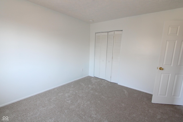 unfurnished bedroom with baseboards, a closet, carpet floors, and a textured ceiling