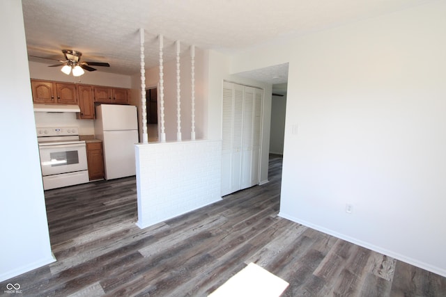 kitchen with under cabinet range hood, white appliances, light countertops, and dark wood-style flooring