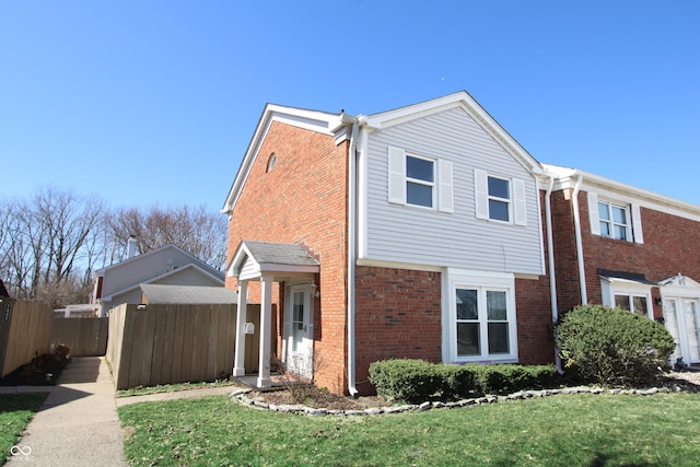 view of side of home with a yard, fence, and brick siding