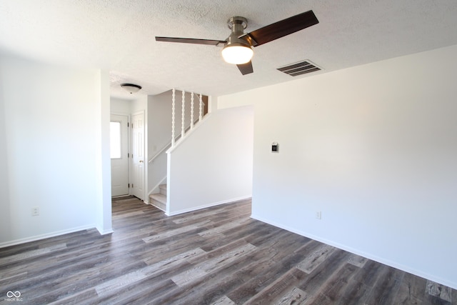 spare room with visible vents, baseboards, stairway, dark wood-style floors, and a textured ceiling