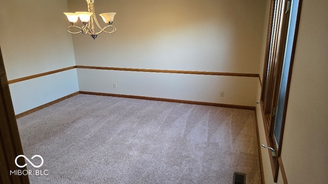 unfurnished room with visible vents, baseboards, carpet floors, and a chandelier