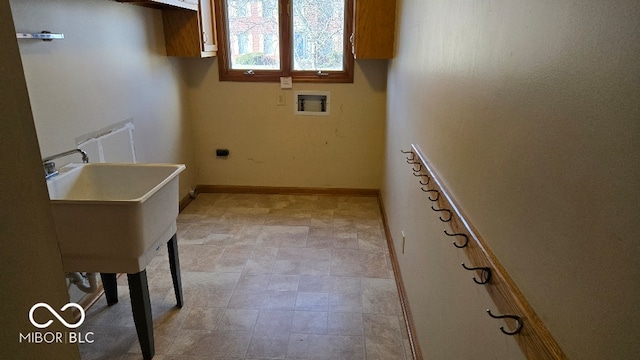 washroom with a sink, radiator heating unit, baseboards, hookup for an electric dryer, and hookup for a washing machine