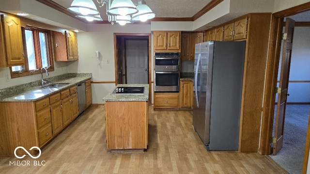 kitchen featuring light wood-style flooring, ornamental molding, a sink, a center island, and appliances with stainless steel finishes