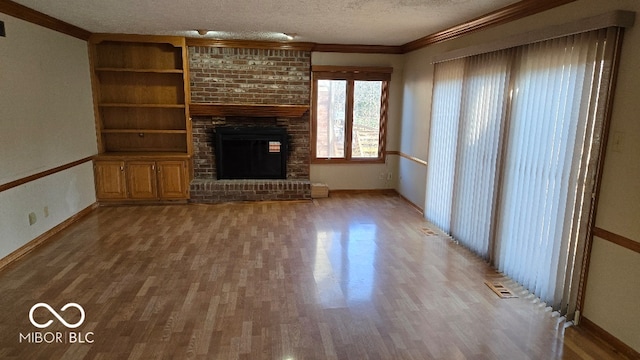 unfurnished living room with ornamental molding, a fireplace, a textured ceiling, and wood finished floors