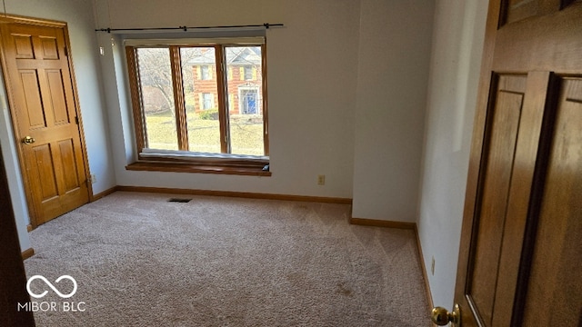 carpeted spare room with visible vents and baseboards