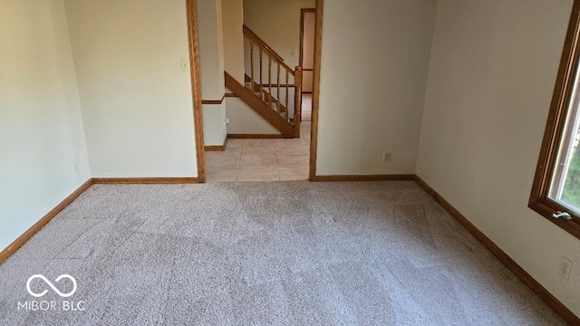 carpeted spare room with stairs and baseboards