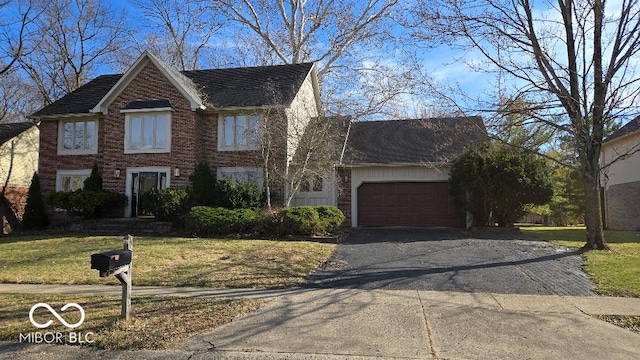 traditional home with a front yard, brick siding, a garage, and driveway