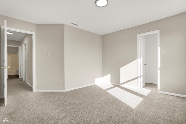 spare room with visible vents, a textured ceiling, baseboards, and carpet