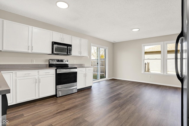 kitchen with dark wood finished floors, white cabinets, and appliances with stainless steel finishes