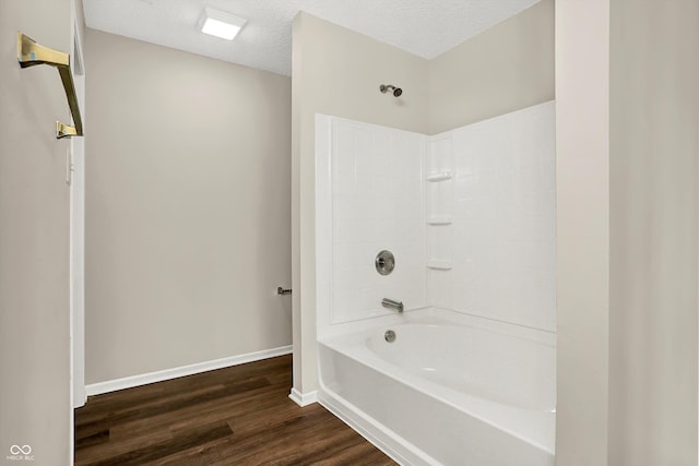 bathroom featuring bathtub / shower combination, wood finished floors, baseboards, and a textured ceiling