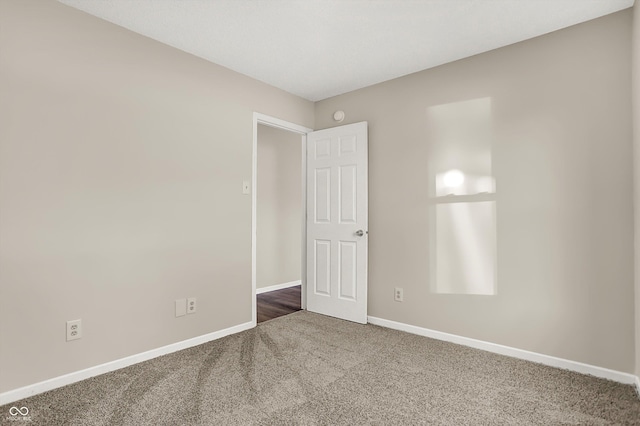 unfurnished room with carpet flooring and baseboards