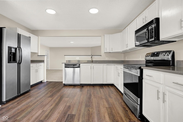 kitchen featuring recessed lighting, stainless steel appliances, dark wood-type flooring, white cabinets, and dark countertops