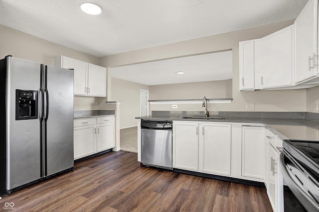 kitchen with a sink, dark wood finished floors, stainless steel appliances, a peninsula, and white cabinets