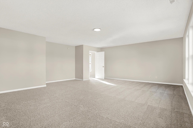 carpeted empty room with baseboards and a textured ceiling