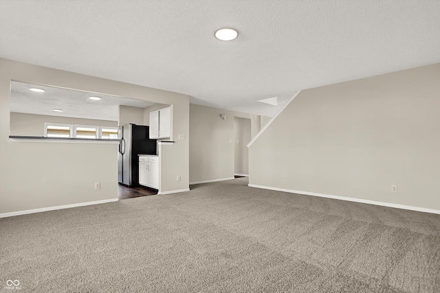 unfurnished living room featuring baseboards, dark carpet, and a textured ceiling