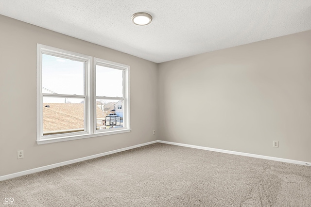 carpeted spare room featuring a textured ceiling and baseboards