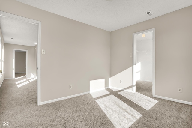 carpeted empty room featuring visible vents, baseboards, and a textured ceiling