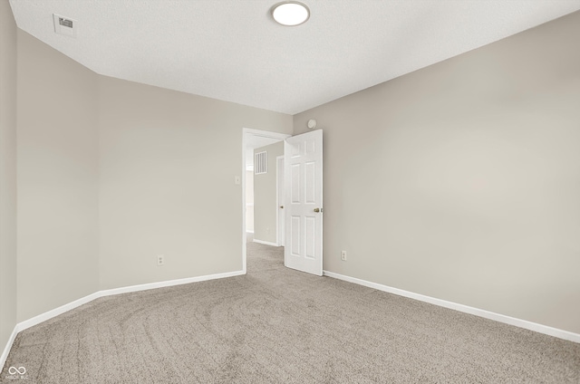 carpeted spare room with visible vents, baseboards, and a textured ceiling