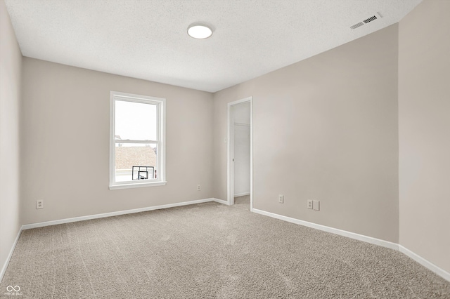 carpeted spare room with visible vents, a textured ceiling, and baseboards