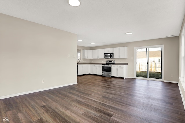 kitchen with baseboards, open floor plan, stainless steel appliances, dark wood-style floors, and white cabinetry