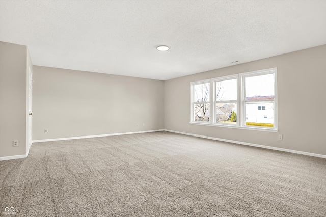 carpeted spare room featuring a textured ceiling and baseboards