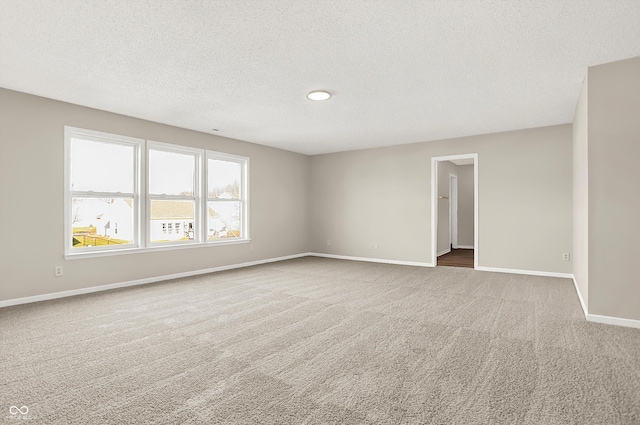 spare room featuring baseboards, a textured ceiling, and carpet floors