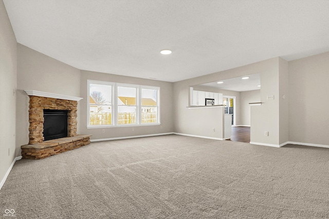 unfurnished living room with carpet flooring, recessed lighting, a fireplace, and baseboards