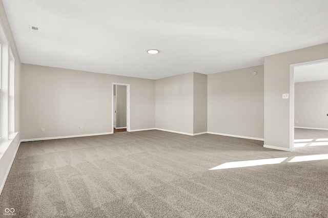 spare room with baseboards and carpet floors