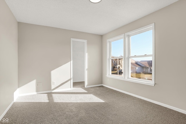 carpeted spare room featuring baseboards and a textured ceiling