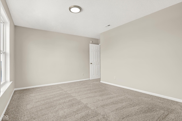 carpeted empty room featuring visible vents, a textured ceiling, and baseboards