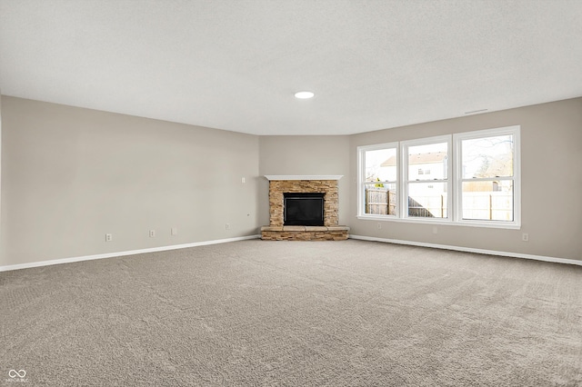 unfurnished living room with a fireplace, baseboards, carpet floors, and a textured ceiling