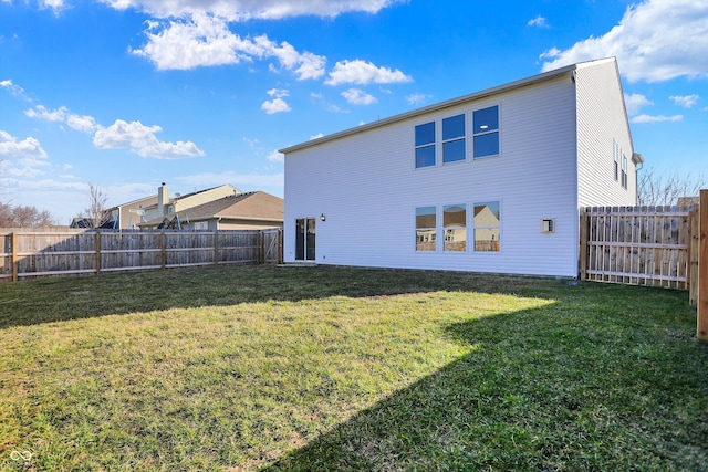 back of house with a lawn and a fenced backyard